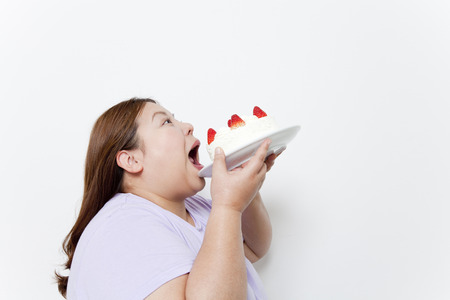 Overweight women dig in to cakeの写真素材