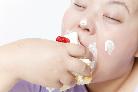 Overweight women dig in to cakeの写真素材