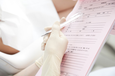 Hand of dental hygienists to write a medical recordの写真素材