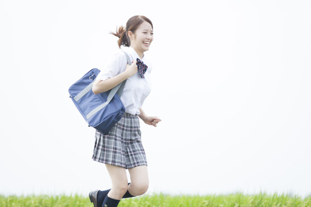 High school girls running the footpathの写真素材