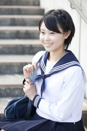 Junior high school girl sitting on stairsの写真素材