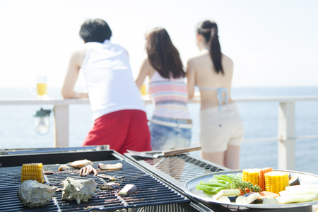 Man and woman staring at the sea and BBQの写真素材