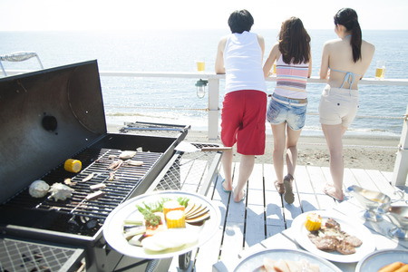 Man and woman staring at the sea and BBQの写真素材