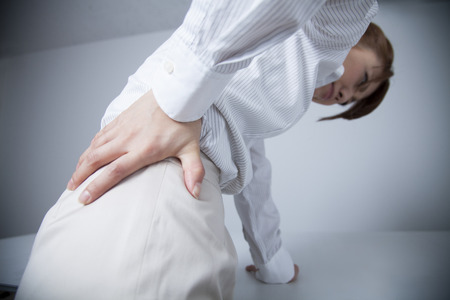 From behind the office lady who suffer from low back painの写真素材