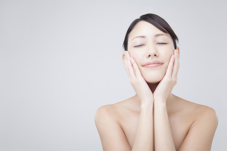 Woman to close the eyes to place your hand on the cheekの写真素材