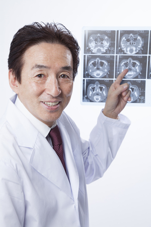 Veteran doctor who is pointing at the X-ray photoの写真素材