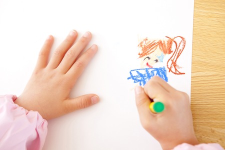 Kindergarten girls draw pictures with crayons in handの写真素材
