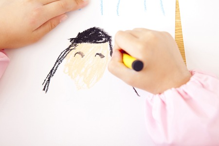 Kindergarten girls draw pictures with crayons in handの写真素材
