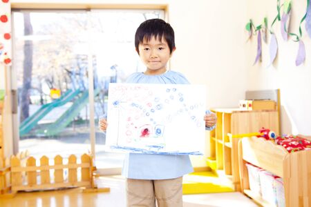 Kindergarten boys to smile with a pictureの写真素材