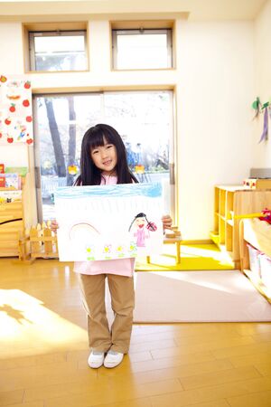 Kindergarten girl to smile with a pictureの写真素材