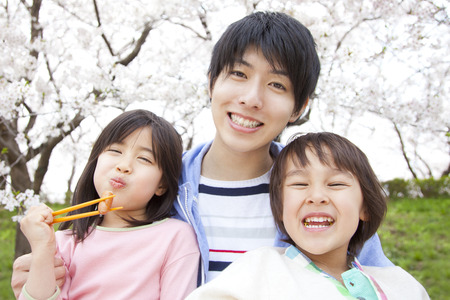 Parents and children eat lunch under the cherry blossomsの写真素材