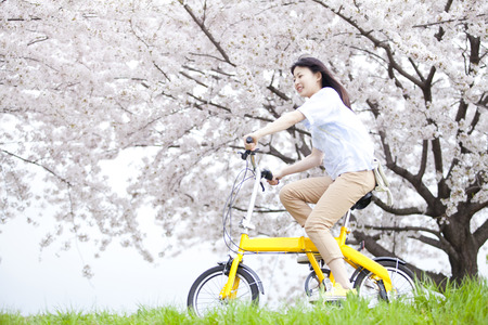 Smile of woman riding a bicycle under the cherry treeの写真素材