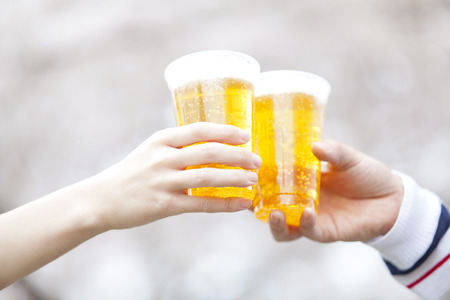 Hand pouring the beer under the cherry treeの写真素材