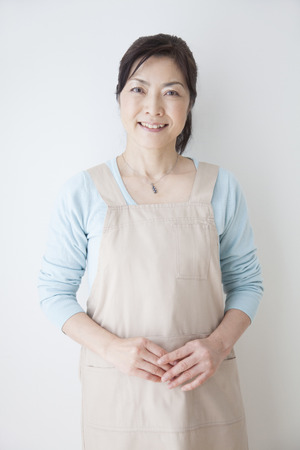 Housewife smile and leaning on the wallの写真素材