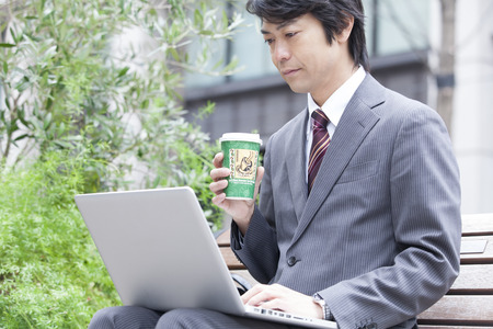 Businessman to operate the notebook PC over a cup of coffeeの写真素材