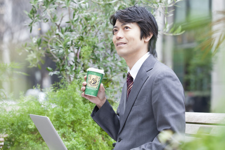 Businessman to operate the notebook PC over a cup of coffeeの写真素材