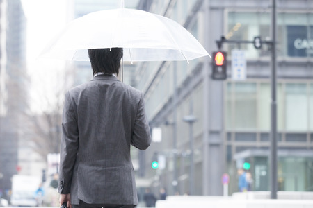 Back shot of businessman holding an umbrellaの写真素材