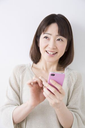 Middle woman smiling with a smartphoneの写真素材