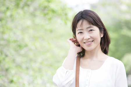 Middle woman smiling in front of the fresh greenの写真素材