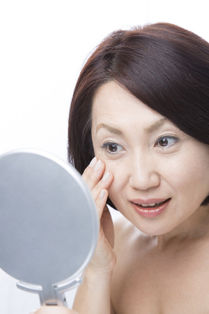 Middle woman to check the skin in the mirrorの写真素材