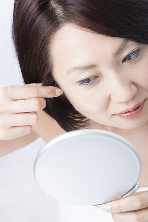 Middle woman to worry about the gray hairの写真素材