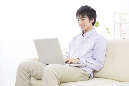 Men who operate the notebook PC sitting on the sofaの写真素材