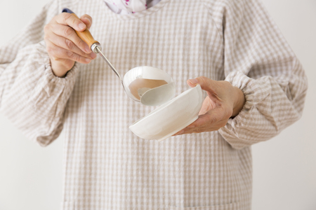 Hand of senior women with a ladle and bowlの写真素材