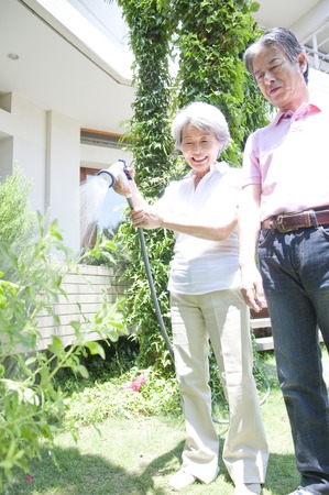 Senior couple of watering in the garden of plantsの写真素材