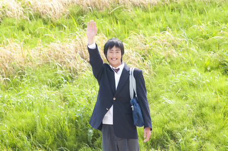 High school boy waving with a smileの写真素材