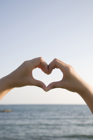 Hand of the woman who made the heart by handの写真素材