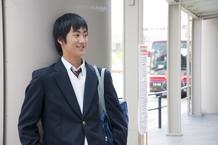 High school boy to be leaning against the pillarの写真素材