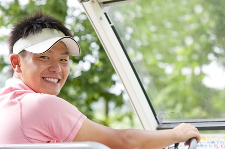 Men smile riding in golf cartの写真素材