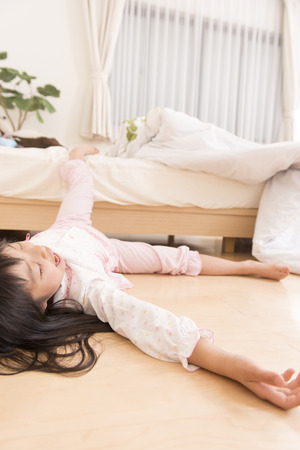 Girl sleeping while tumbled down from the bedの写真素材