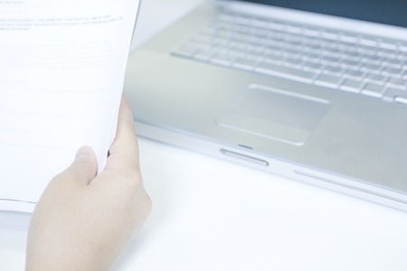 Hand and a notebook computer with a materialのeditorial素材