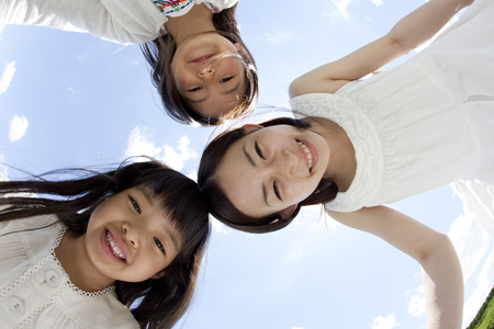 Two girls and a young woman smiling in a circleの写真素材