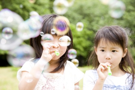 Two girls playing with soap bubblesの写真素材