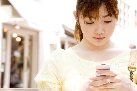 Women to email on the phone sitting on a benchの写真素材