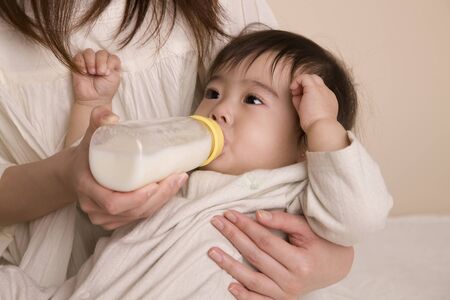 Baby it is embraced by the mother drinking milkの写真素材
