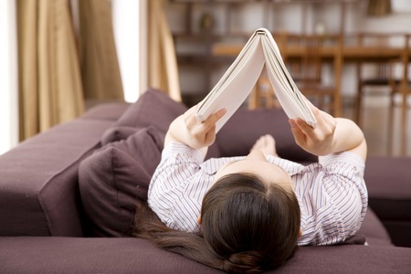 Women read magazines while Nekorogari on the sofaの写真素材