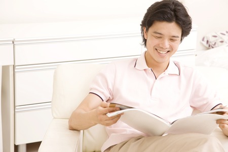 Men read the magazine and sat in a chairの写真素材