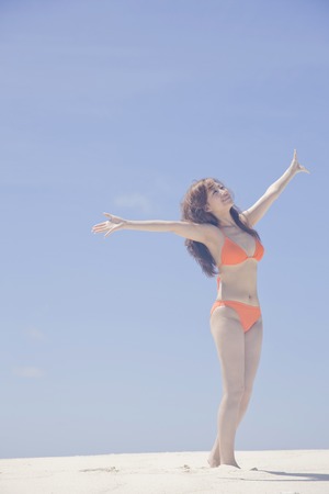 Swimsuit women to spread the hand on the beachの写真素材