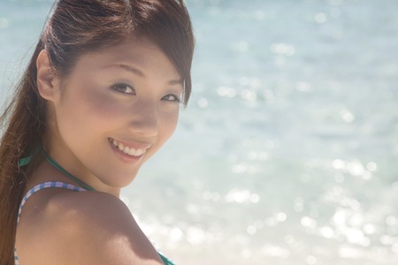 Swimsuit woman of smile that look back at the beachの写真素材