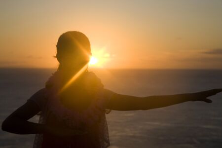 Silhouette of a woman dancing hula at duskの写真素材
