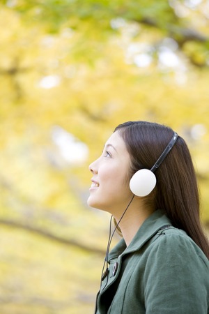 Women who are listening to music under the ginkgo tree-linedの写真素材