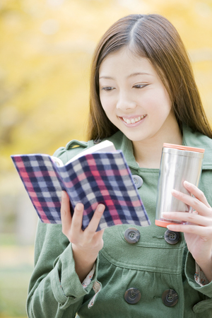 Woman reading a book while having a drinkの写真素材