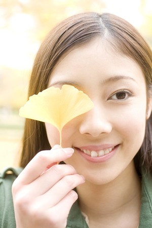 Women who devote ginkgo leaves to faceの写真素材