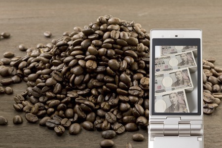 Coffee beans and the cash that goes to the mobile phoneの写真素材