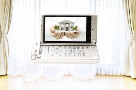 Women with a model of house moves to a mobile screenの写真素材