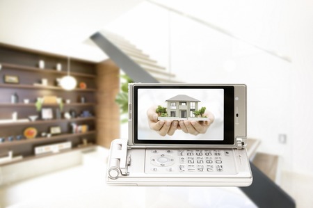 Women with a model of house moves to a mobile screenの写真素材
