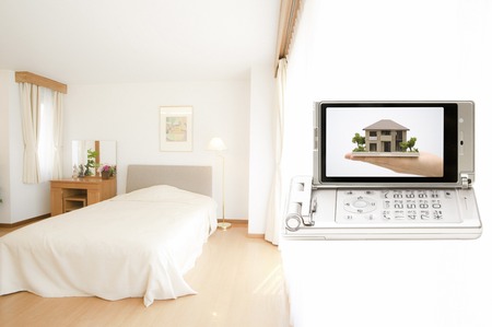 Women with a model of house moves to a mobile screenの写真素材
